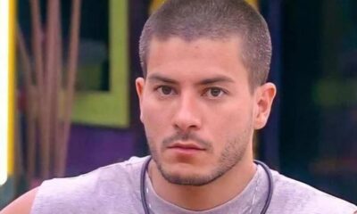 Close-up de Arthur Aguiar, com cabelo curto, barba rala e expressão séria olhando para frente