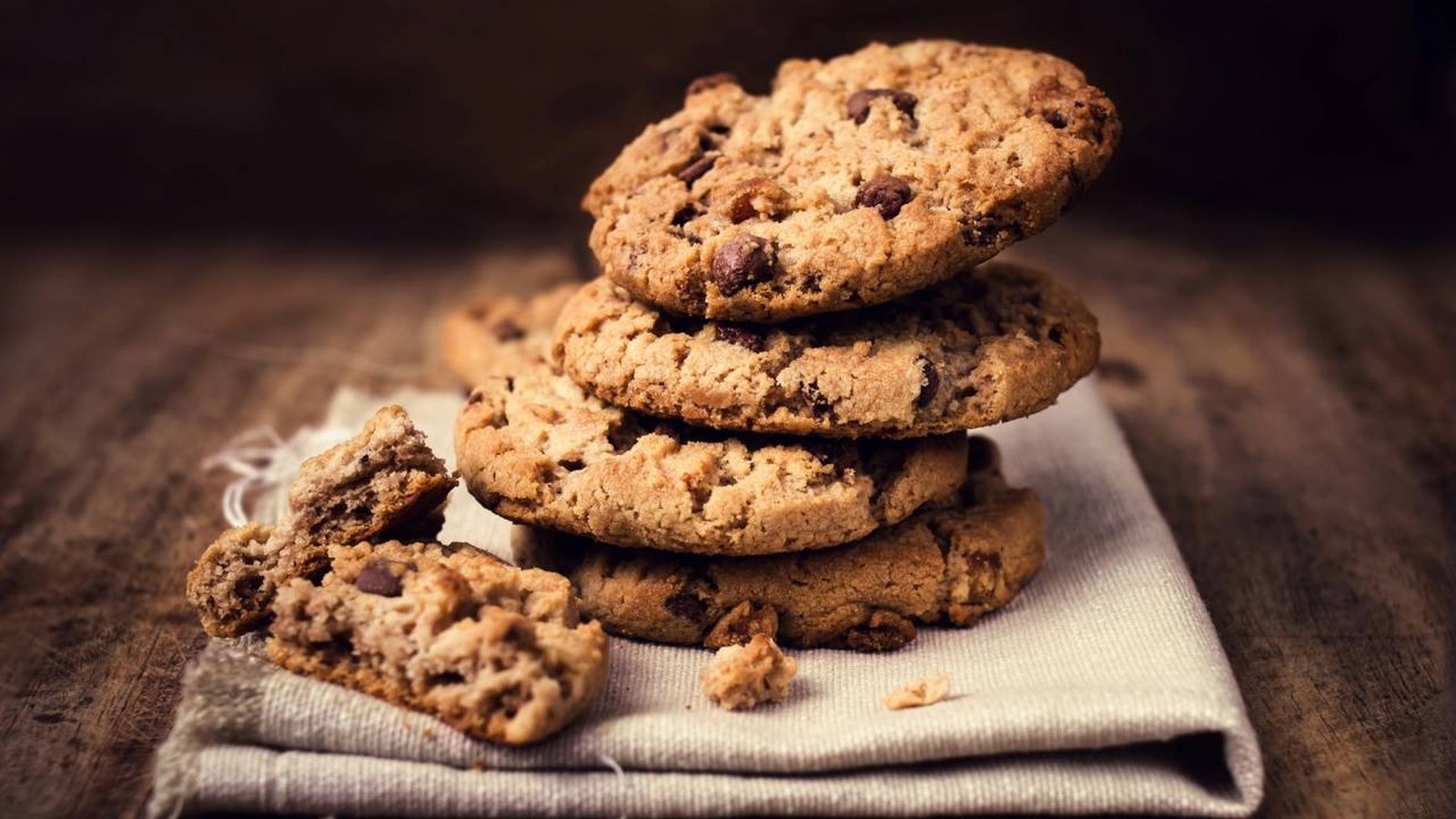 Pilha de cookies com chocolate em pano de linho e madeira