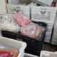 Sacos de carne em caixas de plástico brancas e pretas, com etiquetas 'PALÁCIO CARNES' e 'DACAR'