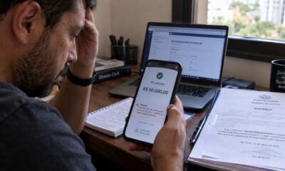 Homem olha celular com Pix de R$ 50 mil enviado e alerta, junto a sentença judicial
