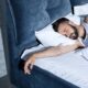 Homem barbudo dormindo profundamente na cama com travesseiro e lençóis brancos
