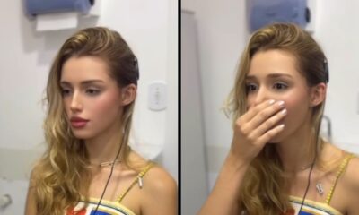 Jovem loira com implante, à direita mão na boca e olhos arregalados