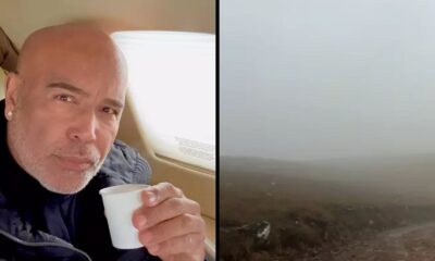 Cantor Rick em aeronave segurando copo, ao lado de paisagem encoberta por neblina densa