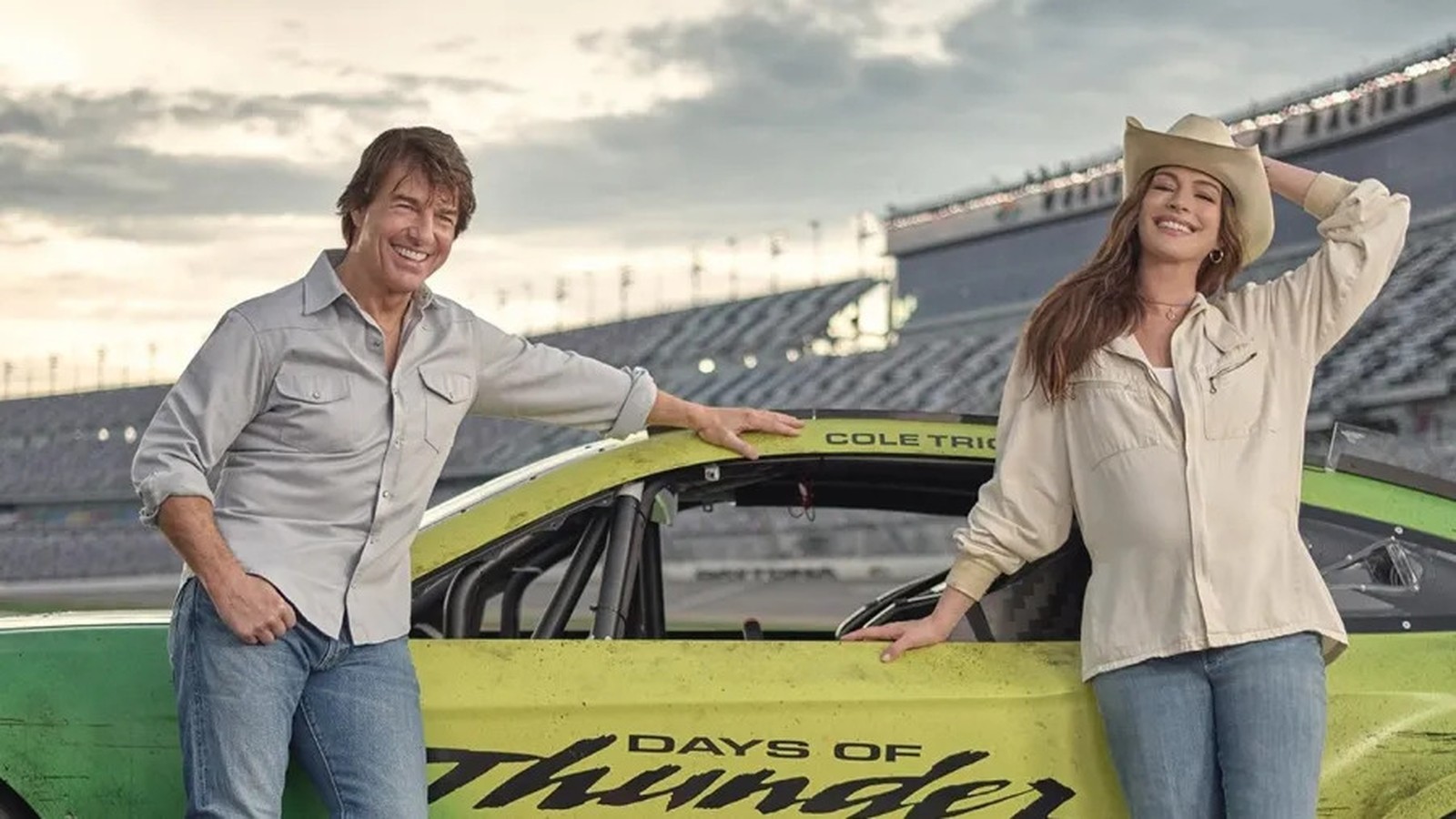 Tom Cruise, Anne Hathaway ao lado de carro de corrida com textos "DAYS OF THUNDER" e "COLE TRICKLE"