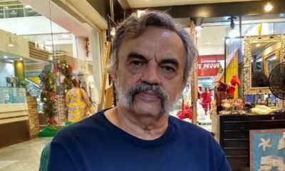 José Dumont, homem de cabelo e bigode grisalhos, vestindo camiseta azul, olhando para frente