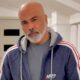Homem careca e barbudo com camiseta cinza e jaqueta azul Aero Postale