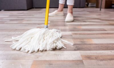 Mop branco molhado no chão de madeira com pessoa limpando