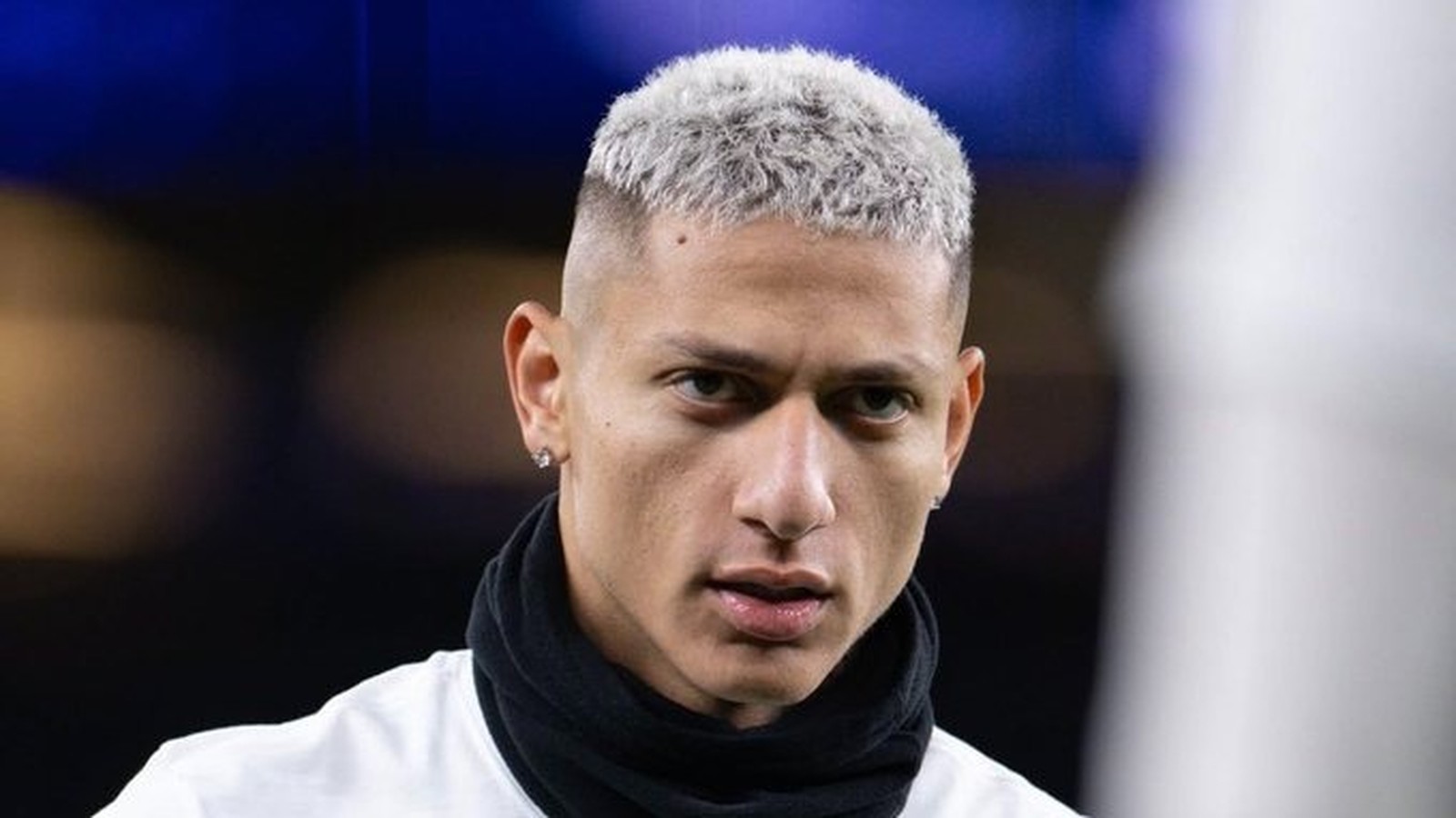 Rosto de Richarlison com cabelo curto platinado, brinco de diamante e cachecol preto