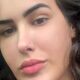 Close-up do rosto de uma mulher com cabelos escuros, olhos castanhos e piercing no nariz