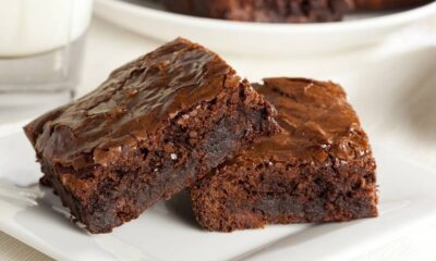 Duas fatias de brownie de chocolate com casquinha rachada e brilhante em prato branco