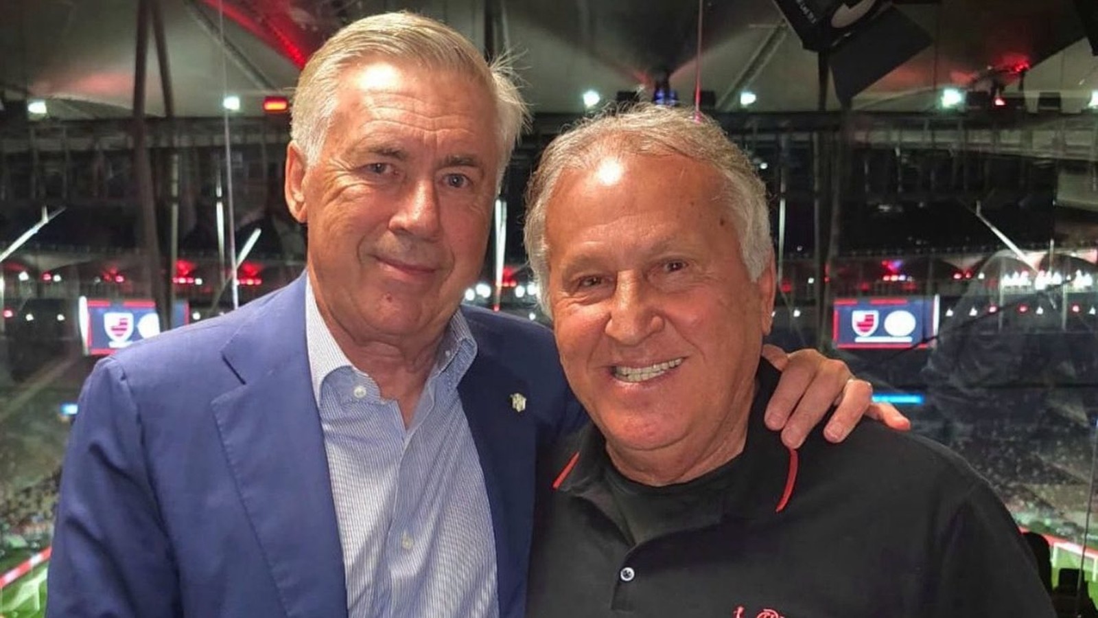 Carlo Ancelotti (esquerda) e Zico (direita) sorrindo em foto juntos, em um estádio