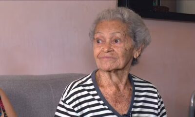 Mulher idosa de cabelos grisalhos e camisa listrada preta e branca olhando para a direita