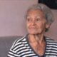 Mulher idosa de cabelos grisalhos e camisa listrada preta e branca olhando para a direita