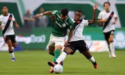 Dois jogadores, um do Palmeiras (verde) e um do Vasco (branco), disputam a bola em campo
