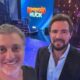 Luciano Huck e Daniel Vorcaro sorrindo no set do programa Domingão com Huck com telão ao fundo