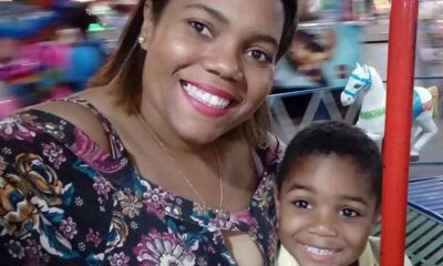 Mulher sorridente e menino em carrossel, com cavalo branco ao fundo
