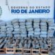 Sacos de maconha em caixotes de madeira e pilhas sob placa "Governo do Estado Rio de Janeiro"
