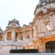 Grande e ornamentado edifício bege com cúpulas, colunas, escadarias brancas e iluminação noturna
