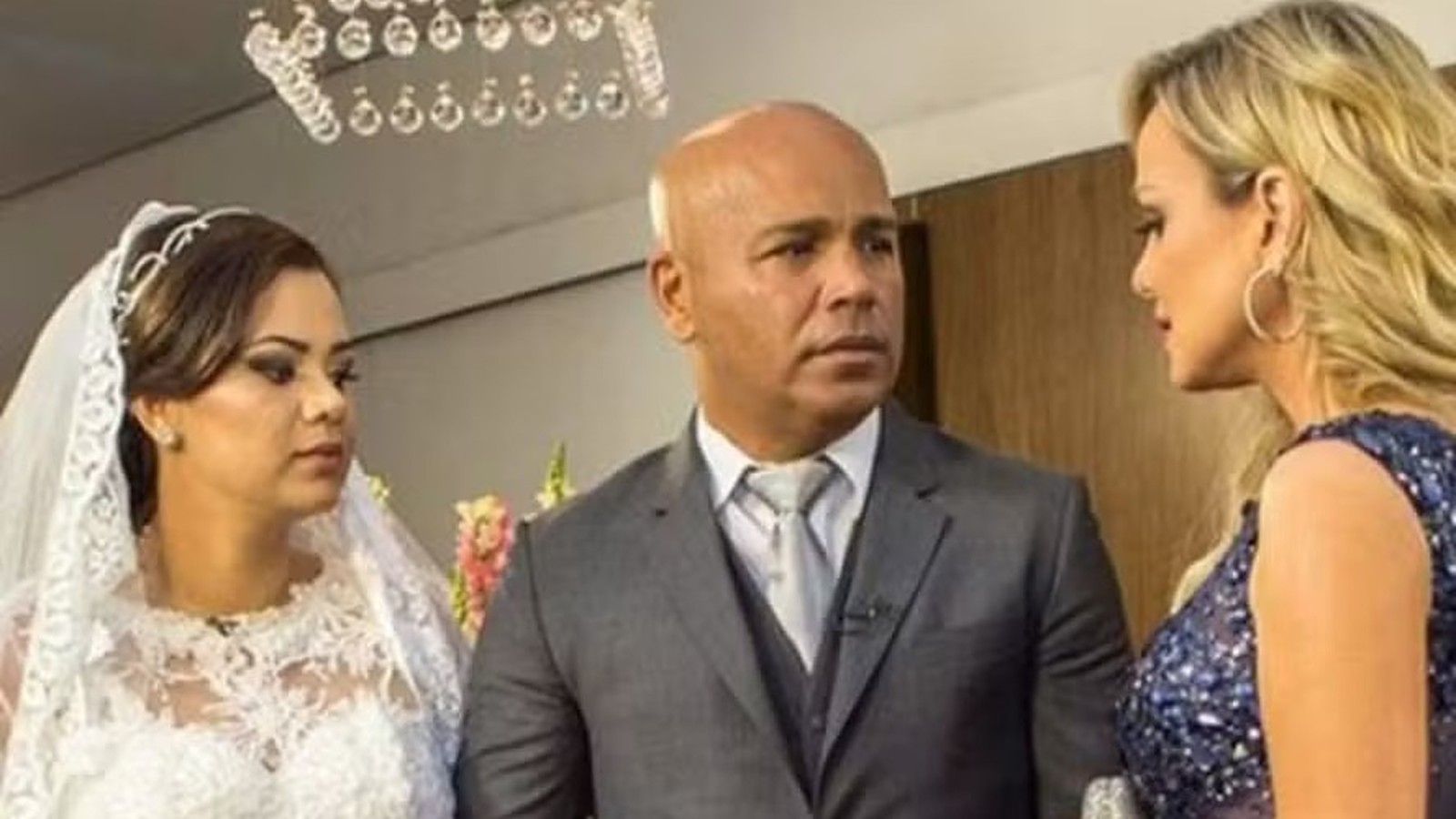 Mulher de noiva, homem de terno e mulher loira em vestido de festa conversando