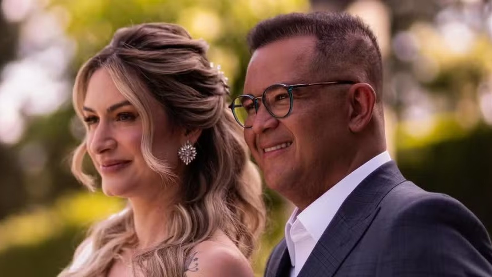 Mulher loira sorridente e homem de óculos sorrindo em um close-up ao ar livre