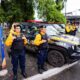 Agentes da Força Municipal com uniformes e viaturas pretas e amarelas estacionadas na rua