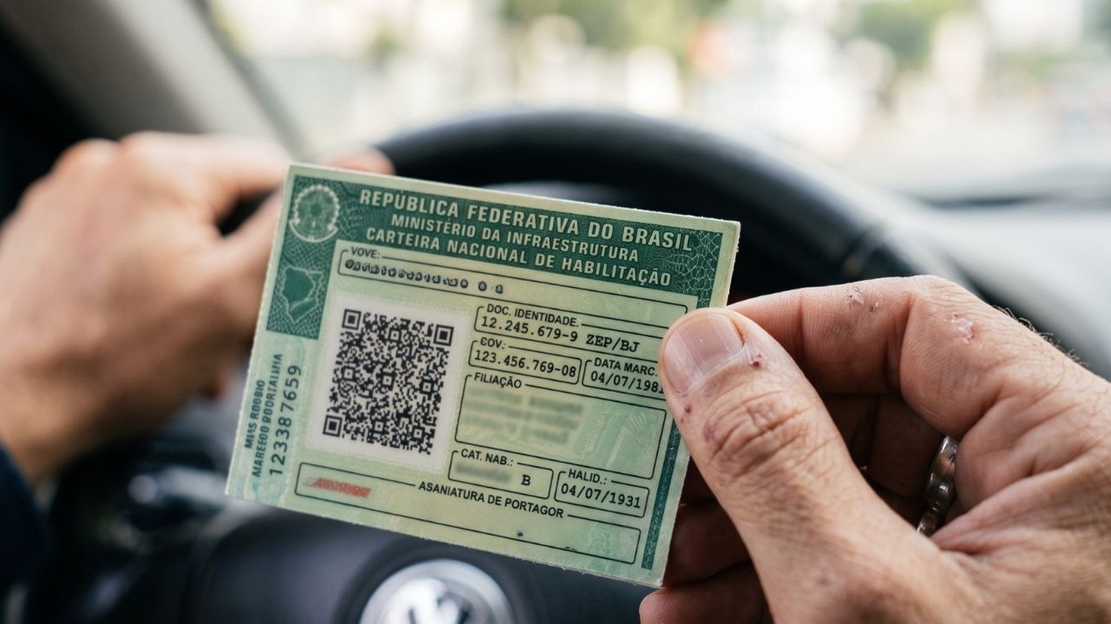 Mãos de motorista segurando a Carteira Nacional de Habilitação verde dentro de um carro