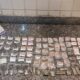 Variedade de drogas embaladas com etiquetas de preço em mesa de granito ao lado de pirâmide da PMERJ
