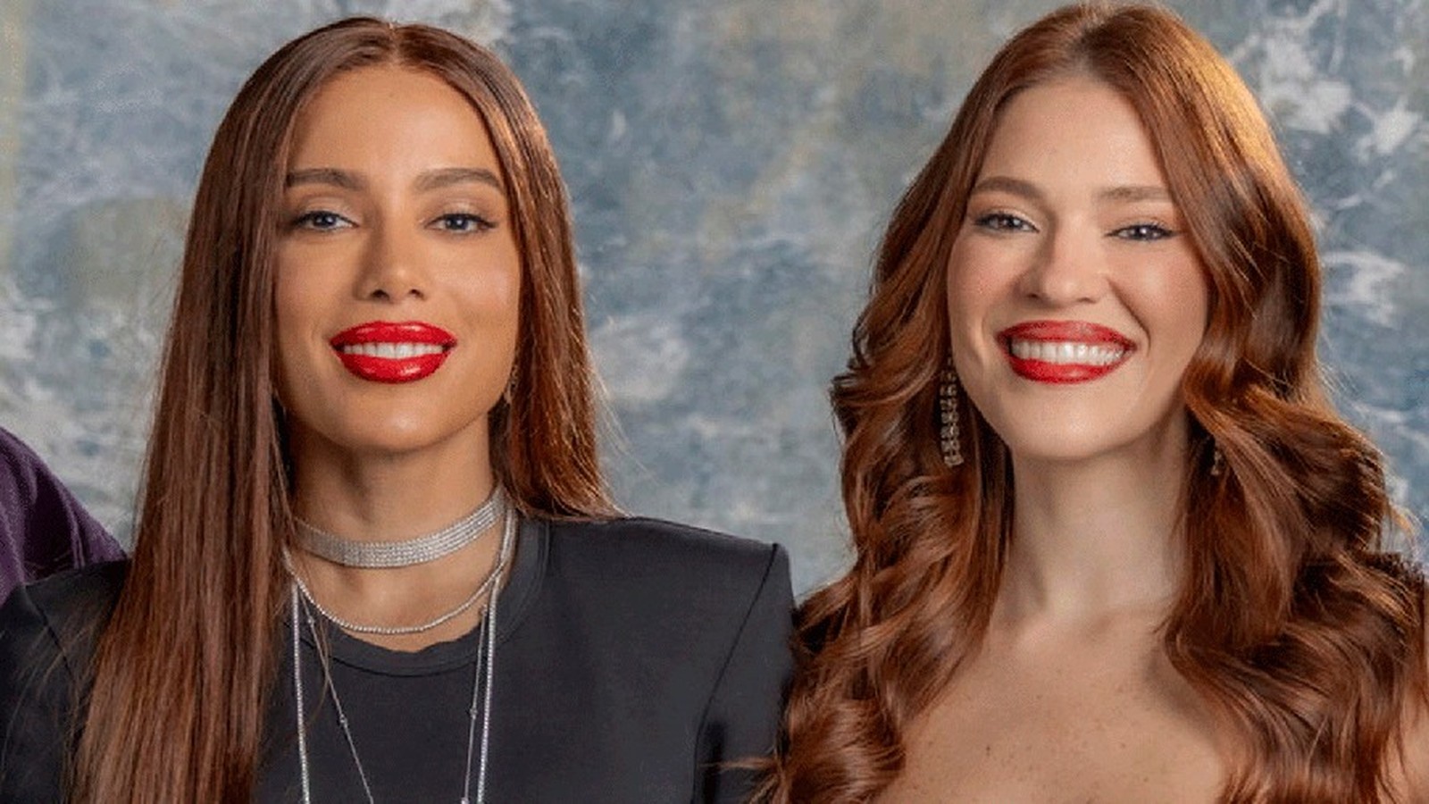 Anitta e Ana Clara, com cabelos castanhos e ruivos, batom vermelho, sorriem para a câmera