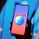 Mão segura smartphone com logo 'Rock in Rio' e ilustração de globo com guitarra na tela.