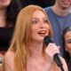 Atriz Marina Ruy Barbosa de cabelo ruivo falando em microfone, sorrindo