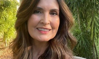 Fátima Bernardes sorrindo em close-up, com cabelos castanhos e fundo de folhagem verde