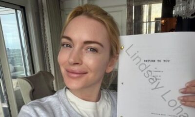 Lindsay Lohan sorrindo, segurando roteiro "Return to You" com seu nome em marca d'água.
