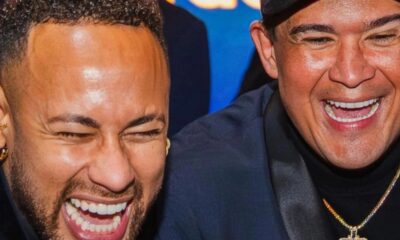 Neymar e Bruno Avelar, com brincos e colar, rindo muito com os olhos fechados