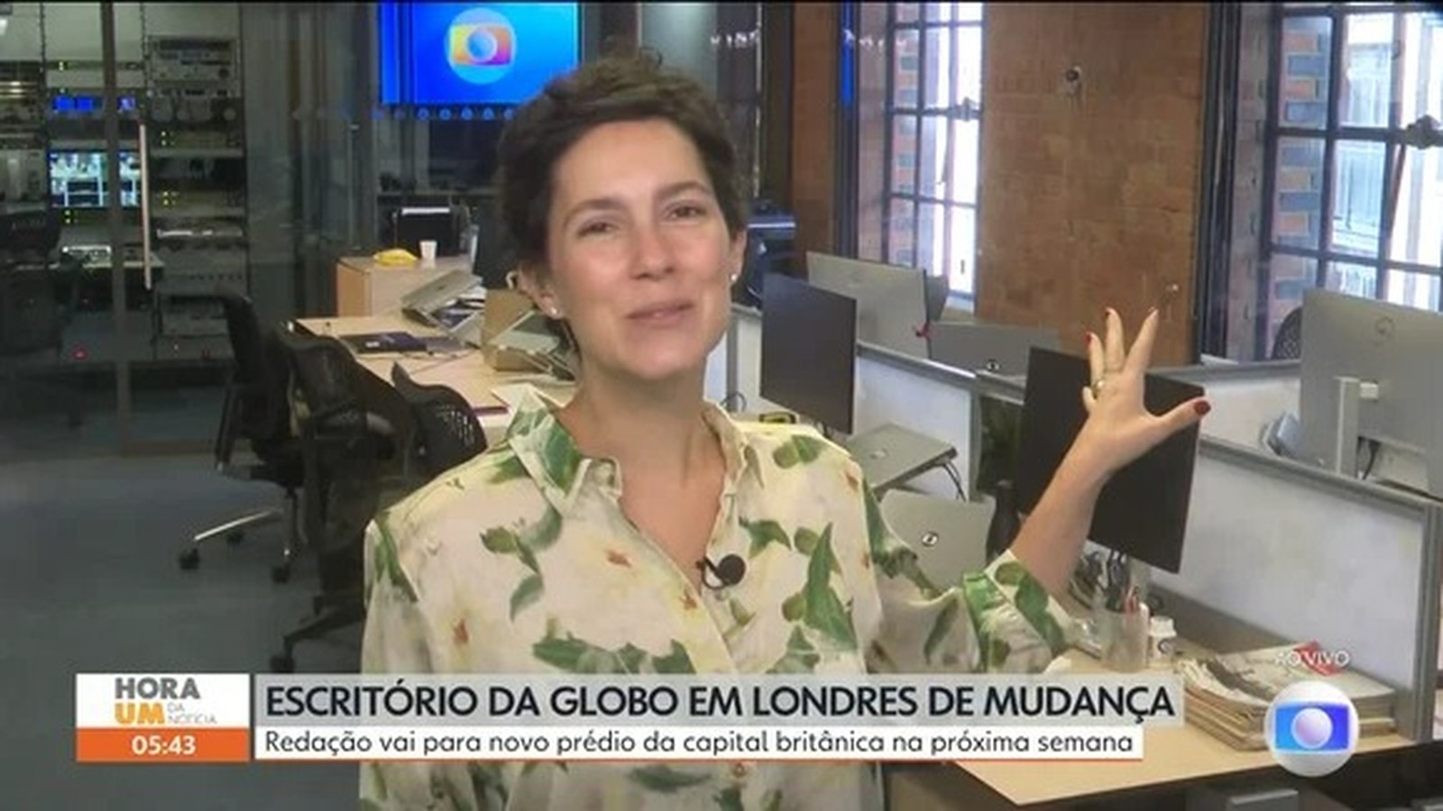 Cecília Malan em escritório, apontando, com gráfico sobre mudança da Globo Londres na tela