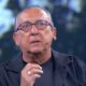 Galvão Bueno, de óculos, microfone e anel, fala em estúdio de TV. #Domingão