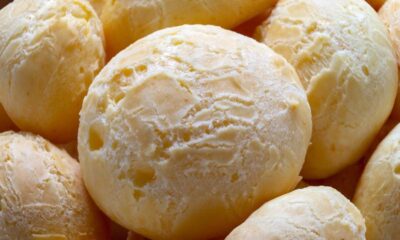 Close-up de vários pães de queijo redondos, recém-assados, com superfície rachada e clara