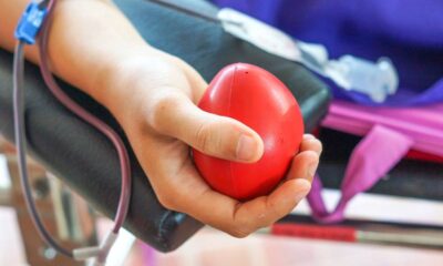 Close-up de um braço doando sangue, segurando uma bola vermelha de apertar