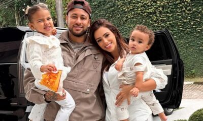 Neymar, Bruna Biancardi, Mavie e Mel posam juntos sorrindo, com carro e folhagem ao fundo
