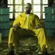 Walter White de Breaking Bad em traje amarelo, sentado, rodeado por dinheiro e metanfetamina azul.