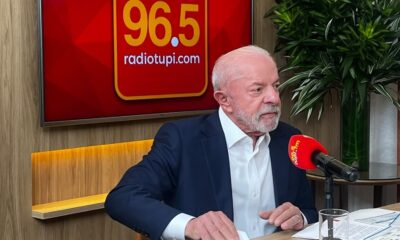 Luiz Inácio Lula da Silva fala em microfone vermelho da Rádio Tupi. Fundo com logo 96.5
