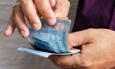Mãos seguram e contam cédulas de dinheiro brasileiro