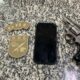 Dois distintivos do GOE, um celular preto com tela rachada e um revólver oxidado