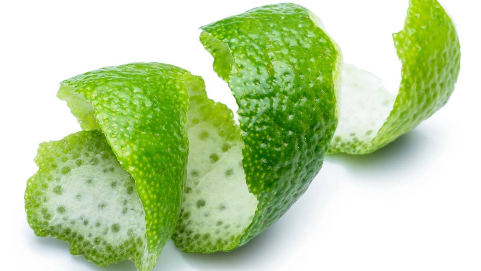 Casca verde de limão torcida com interior branco e textura pontilhada em fundo branco