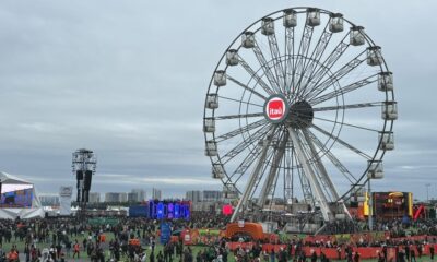 Uma roda gigante Itaú em um festival lotado com público e palcos sob céu nublado