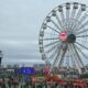 Uma roda gigante Itaú em um festival lotado com público e palcos sob céu nublado