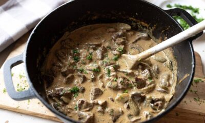 Close-up de strogonoff cremoso com frango e champignon em panela de ferro com colher de madeira