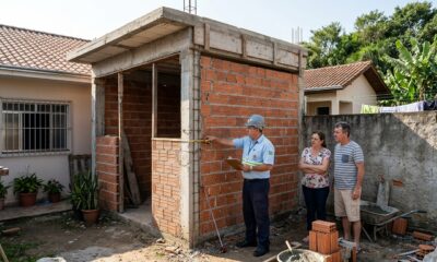 Casal começa a construir a edícula colada no muro do vizinho, acredita que dentro do próprio lote não precisa deixar recuo, e a prefeitura embarga a obra explicando o que o Código de Obras exige