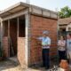 Casal começa a construir a edícula colada no muro do vizinho, acredita que dentro do próprio lote não precisa deixar recuo, e a prefeitura embarga a obra explicando o que o Código de Obras exige