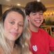 Mulher sorridente com cabelos loiros e jovem sorridente de cabelos escuros em foto de perto