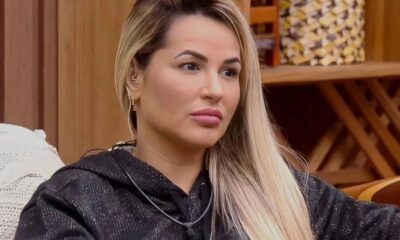 Deolane Bezerra, mulher loira de cabelos longos, olhar sério, batom rosa e moletom preto